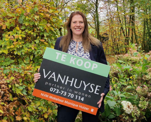 Makelaar Monique Huizer met een verkoopbord